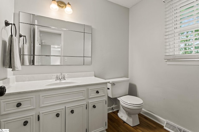 bathroom with visible vents, vanity, wood finished floors, toilet, and baseboards
