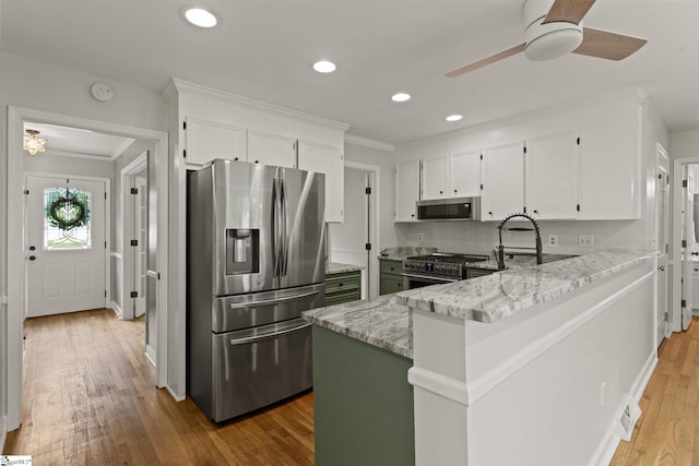 kitchen featuring crown molding, stainless steel appliances, a ceiling fan, and light stone counters