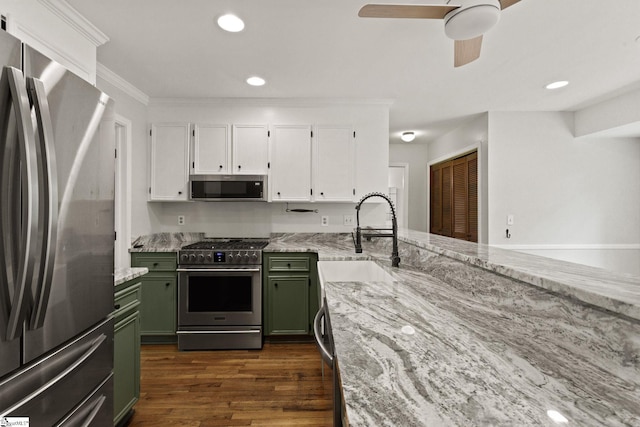 kitchen featuring white cabinets, light stone counters, appliances with stainless steel finishes, a sink, and green cabinets