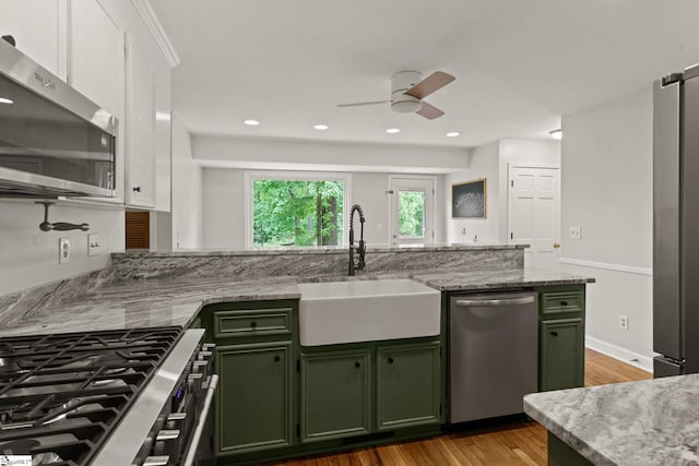 kitchen featuring ceiling fan, white cabinetry, a sink, green cabinets, and stainless steel appliances