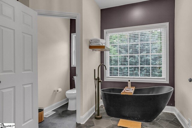 268 Antrim Ave, Moore, SC 29369 - bathroom with toilet, baseboards, a freestanding bath, and tile patterned flooring