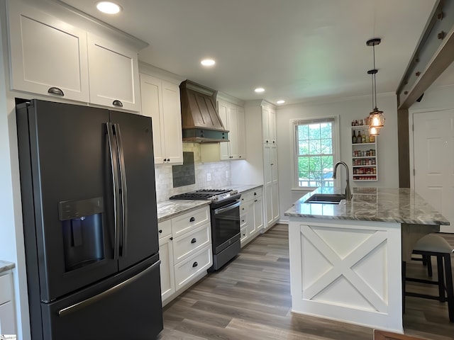 kitchen with decorative backsplash, custom exhaust hood, black fridge, a sink, and gas stove