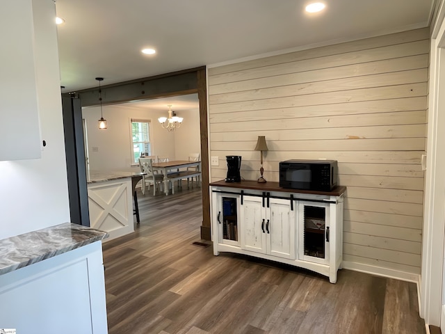 bar featuring black microwave, an inviting chandelier, wood walls, recessed lighting, and dark wood-style floors