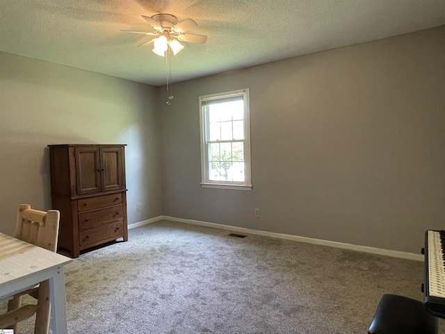 office area featuring a ceiling fan, a textured ceiling, light colored carpet, visible vents, and baseboards