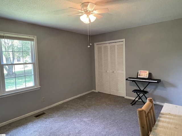unfurnished bedroom with a closet, visible vents, baseboards, dark colored carpet, and a textured ceiling