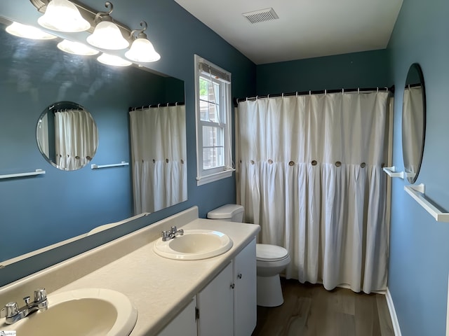 bathroom featuring visible vents, a sink, wood finished floors, and toilet