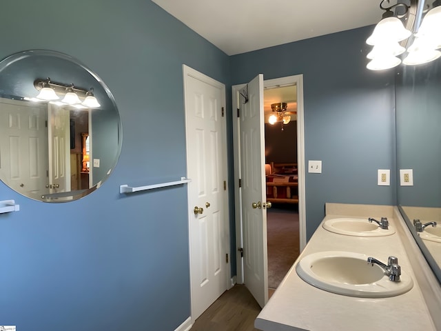 bathroom with double vanity, a sink, wood finished floors, and a notable chandelier