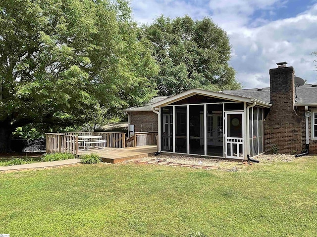 back of house with a yard, a wooden deck, and a sunroom