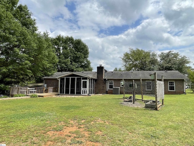 back of property with a sunroom, central AC unit, a yard, and a chimney