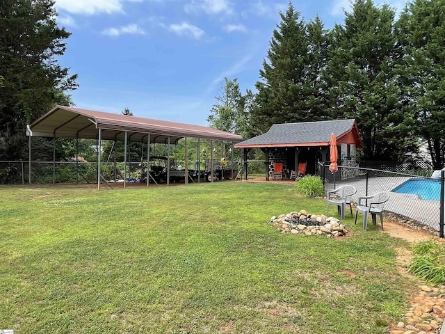 view of yard with a fenced in pool, an outdoor fire pit, fence, and a carport