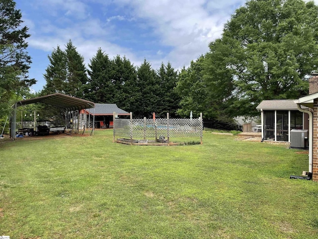view of yard with a sunroom, central AC, fence, and a detached carport