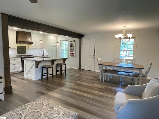 living room featuring crown molding, baseboards, an inviting chandelier, and dark wood finished floors