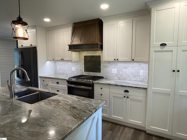kitchen featuring gas range, a sink, freestanding refrigerator, custom range hood, and white cabinetry