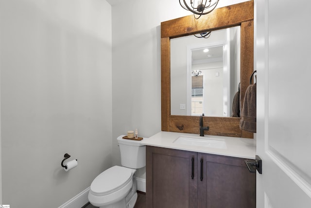 half bathroom with vanity, baseboards, and toilet