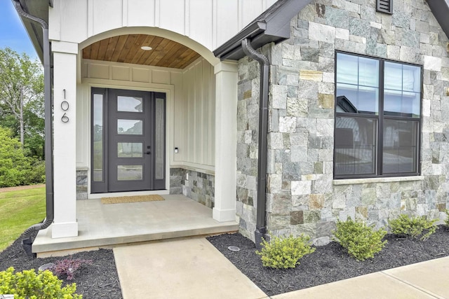 doorway to property with board and batten siding and stone siding