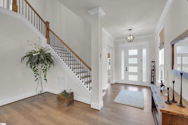 entryway featuring stairs, crown molding, visible vents, and wood finished floors
