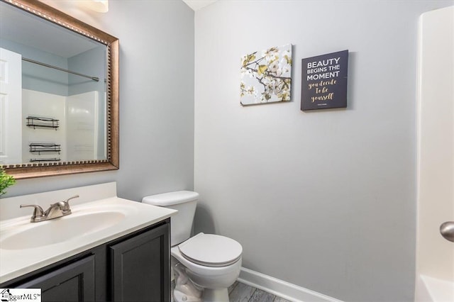 full bath with vanity, wood finished floors, toilet, baseboards, and walk in shower