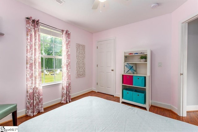bedroom featuring baseboards, ceiling fan, wood finished floors, and visible vents