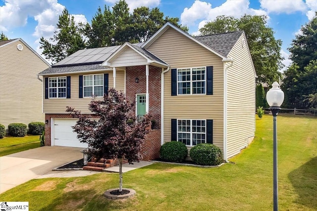 raised ranch featuring a garage, brick siding, roof mounted solar panels, a front lawn, and concrete driveway