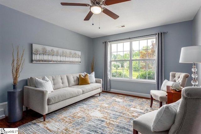 living area with a ceiling fan, baseboards, visible vents, and wood finished floors