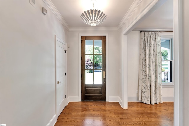 entrance foyer with a chandelier, baseboards, wood finished floors, visible vents, and ornamental molding