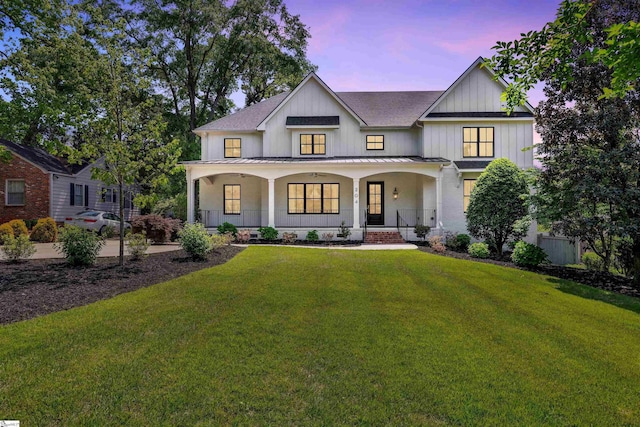 modern farmhouse featuring covered porch, a standing seam roof, a shingled roof, metal roof, and a lawn