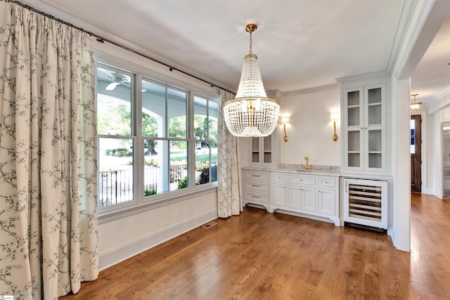 unfurnished dining area featuring beverage cooler, ornamental molding, plenty of natural light, and visible vents