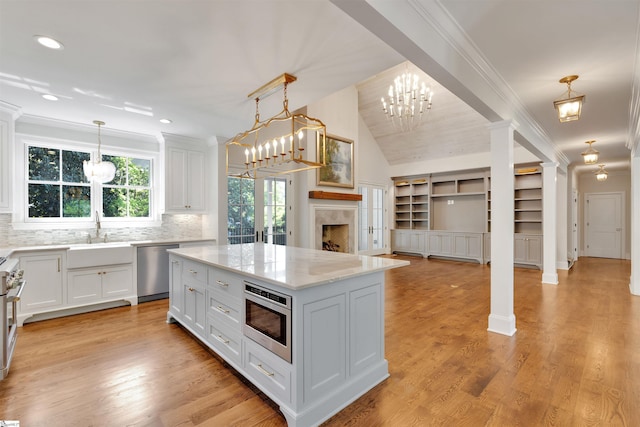 kitchen with a kitchen island, a sink, open floor plan, stainless steel appliances, and ornate columns