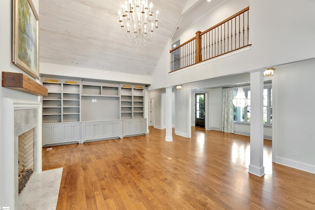 unfurnished living room featuring ornate columns, wood ceiling, wood finished floors, and a notable chandelier