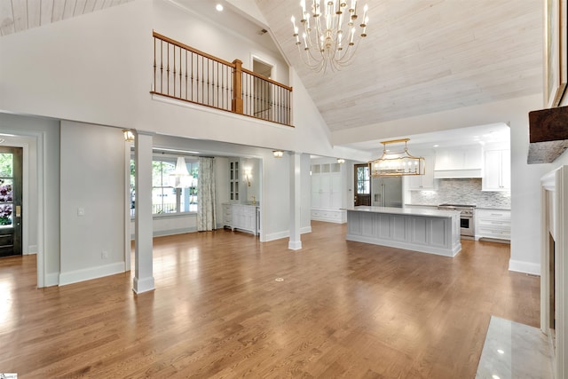unfurnished living room featuring wood ceiling, light wood finished floors, a chandelier, and high vaulted ceiling