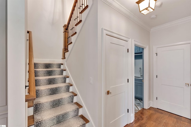 staircase with crown molding and wood finished floors
