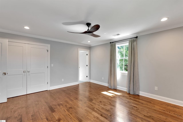 unfurnished bedroom featuring crown molding, baseboards, visible vents, and wood finished floors