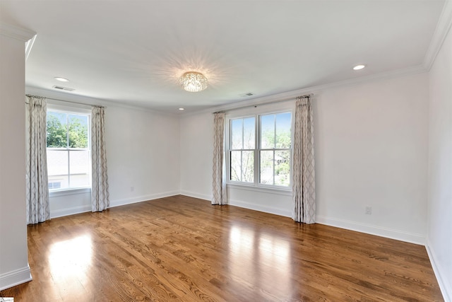 empty room featuring visible vents, baseboards, crown molding, and wood finished floors