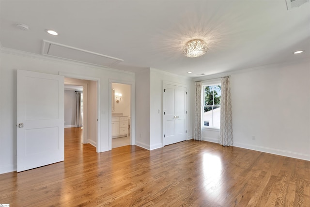 spare room with crown molding, attic access, light wood finished floors, and visible vents