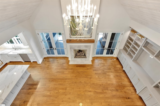 interior space with high vaulted ceiling, an inviting chandelier, a wealth of natural light, and french doors