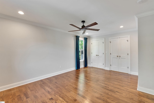 unfurnished bedroom featuring two closets, recessed lighting, baseboards, and ornamental molding