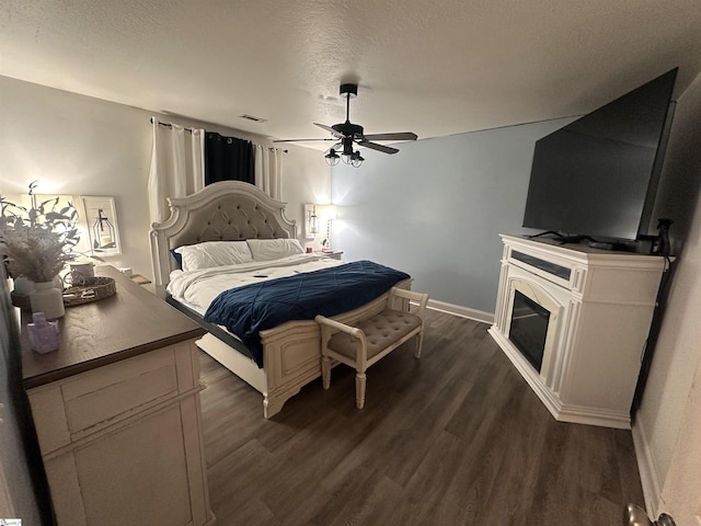 bedroom featuring ceiling fan, dark wood-style flooring, a textured ceiling, visible vents, and baseboards