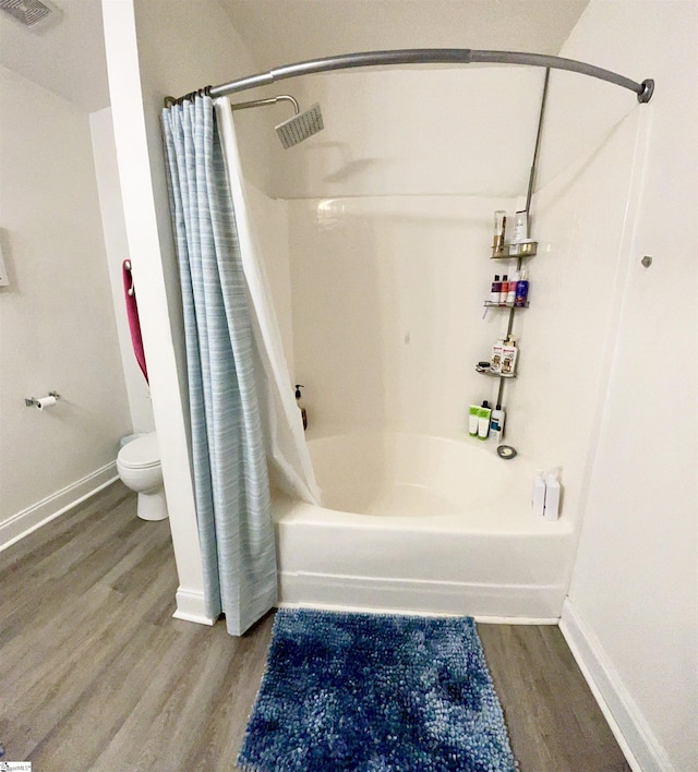 full bathroom with toilet, shower / bath combo with shower curtain, baseboards, wood finished floors, and visible vents