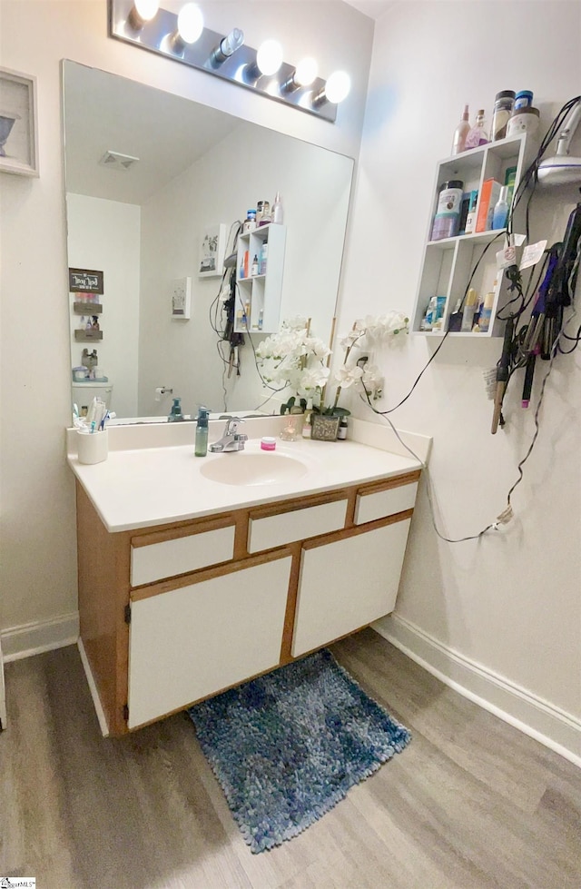 bathroom featuring baseboards, wood finished floors, visible vents, and vanity