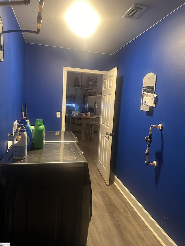 bedroom featuring baseboards, independent washer and dryer, wood finished floors, and visible vents