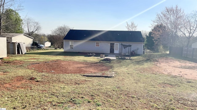 rear view of house featuring fence and a lawn