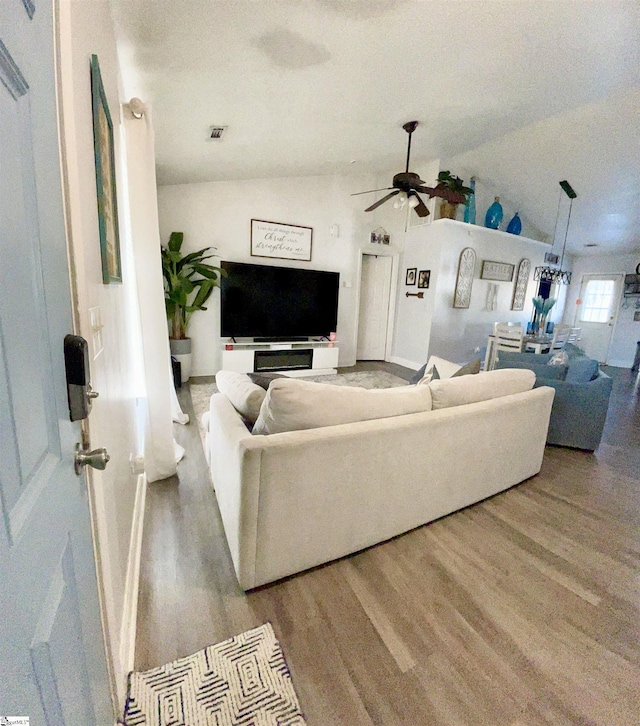 living room featuring baseboards, ceiling fan, vaulted ceiling, and wood finished floors