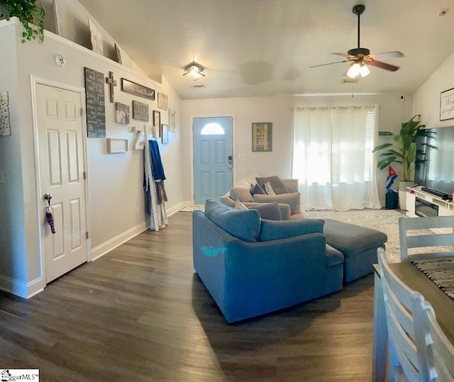 living room with a ceiling fan, baseboards, vaulted ceiling, and dark wood-type flooring