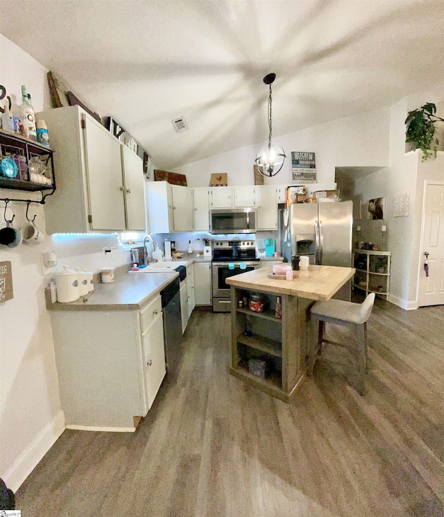 kitchen with appliances with stainless steel finishes, a sink, light countertops, lofted ceiling, and dark wood-type flooring