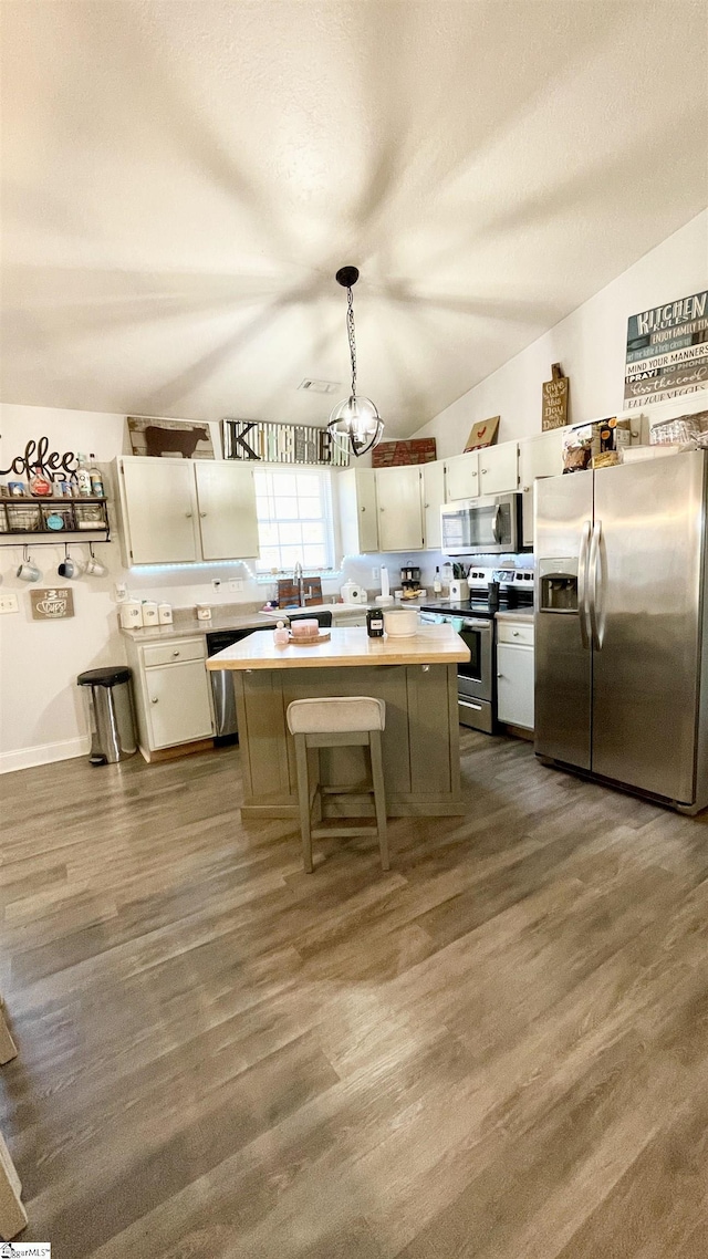 kitchen featuring light countertops, dark wood finished floors, a center island, stainless steel appliances, and white cabinetry