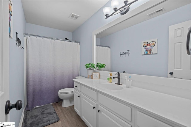bathroom with visible vents, wood finished floors, toilet, and vanity
