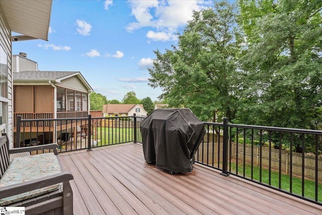 wooden terrace featuring area for grilling, fence, and a sunroom