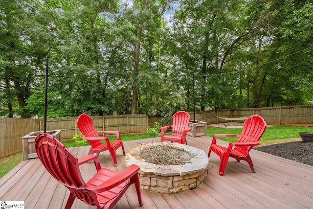wooden terrace with a fenced backyard and an outdoor fire pit