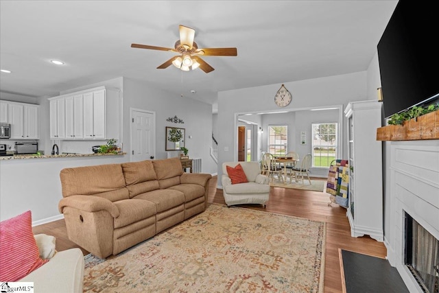living area featuring recessed lighting, a fireplace with flush hearth, ceiling fan, and wood finished floors