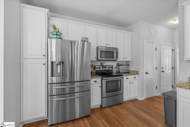 kitchen with light stone counters, dark wood finished floors, appliances with stainless steel finishes, and white cabinets